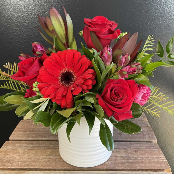 Red roses and a gerbera daisy in a white vase