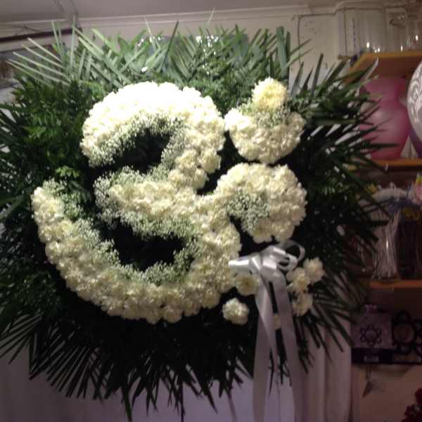 Large white floral funeral wreath with a ribbon bow