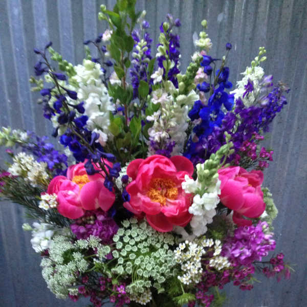 Tall bouquet of pink peonies and purple-white snapdragons in a wrapped vase