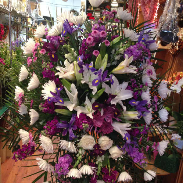 Large standing floral spray with white lilies, purple irises, and pink blooms