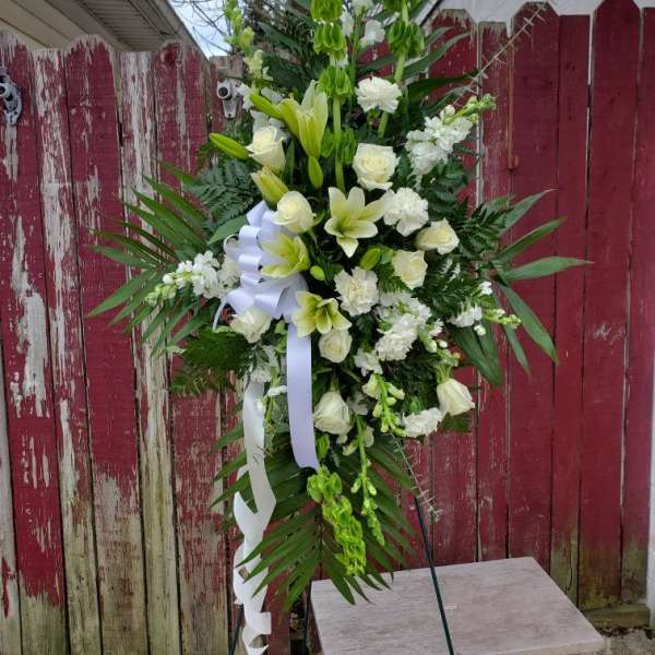 Tall white floral standing spray with ribbon on an easel