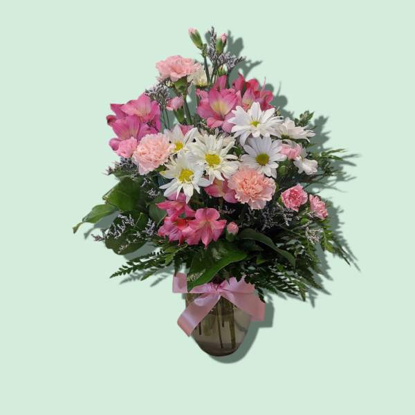 Pink and white mixed bouquet in a glass vase with a pink ribbon