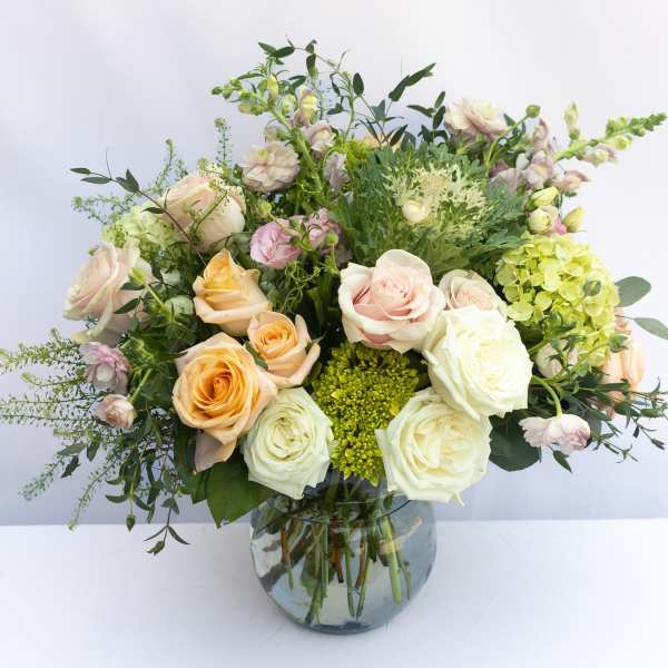 Mixed pastel roses and greenery in a glass vase