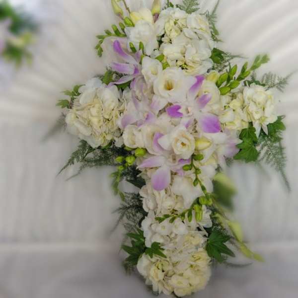 White floral cross-shaped arrangement with pale purple accents