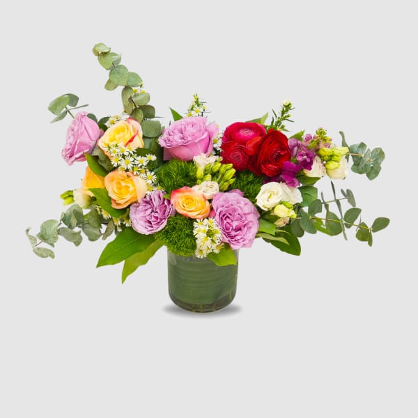 Mixed bouquet of pink, red, and peach roses in a glass vase