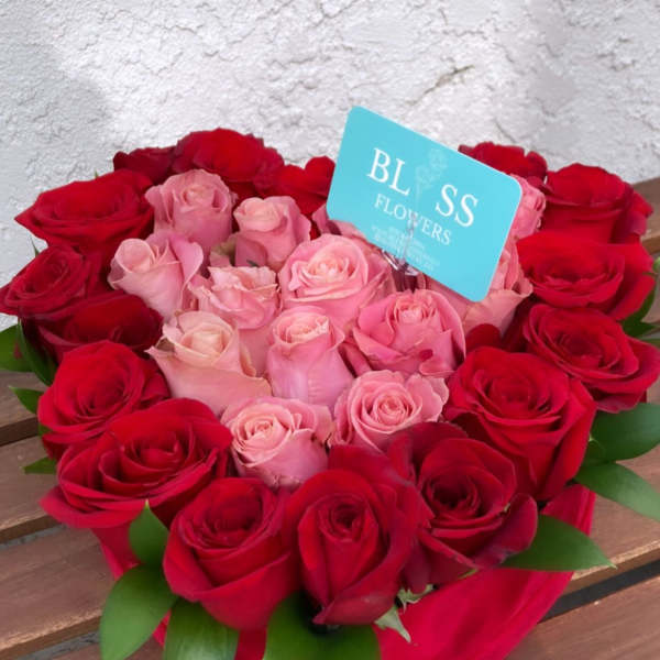Heart-shaped bouquet of red and pink roses with a blue card