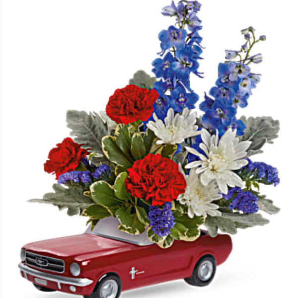 Red toy car topped with red, white, and blue flowers