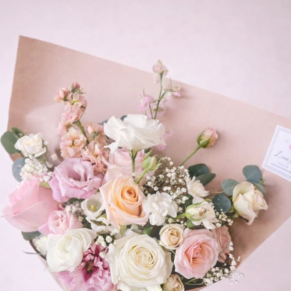Hand-tied bouquet of pink and white roses with small white filler flowers