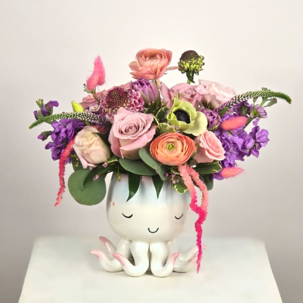 Mixed pink and purple flower arrangement in a white octopus planter