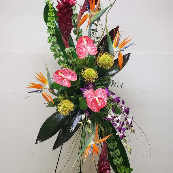 Tall tropical standing spray with red, orange, pink, and green flowers on a black metal easel