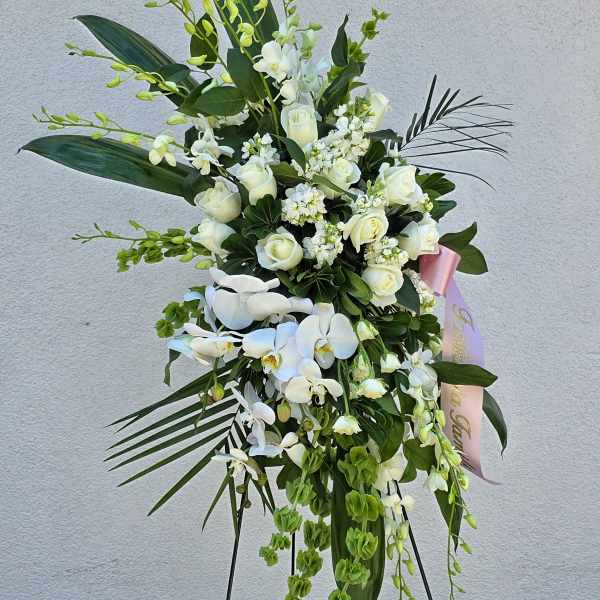 Tall white floral standing spray with orchids and roses on an easel