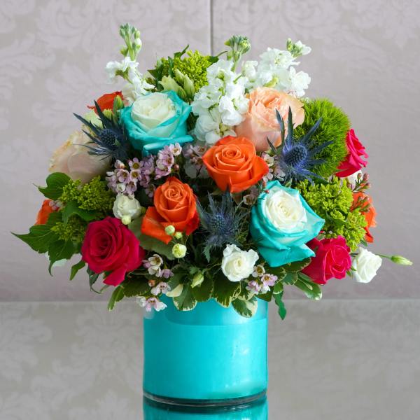 Colorful bouquet of roses and white flowers in a turquoise vase