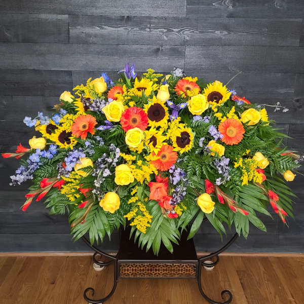 Large mixed floral spray with yellow roses and sunflowers in a black stand