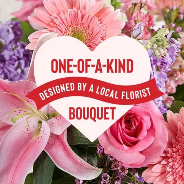 Pink bouquet with lilies, roses, and daisies behind a heart-shaped label