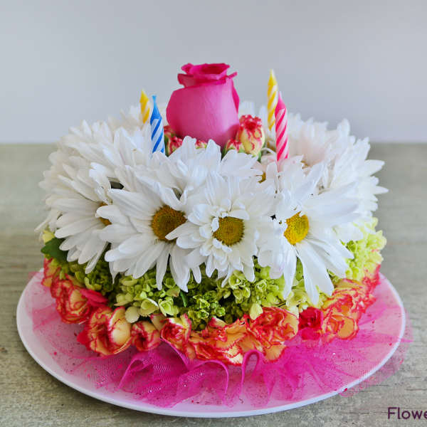 Flower cake with white daisies, pink rose, and striped candles