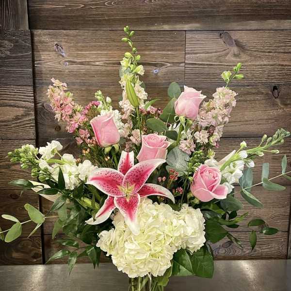 Pink roses and a pink stargazer lily in a glass vase
