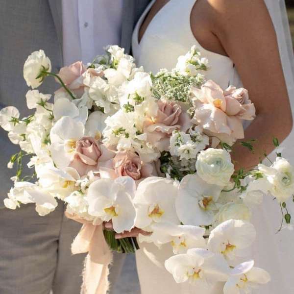Bride holding a white and blush wedding bouquet with orchids and roses