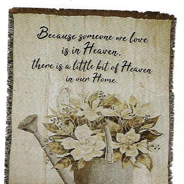 Decorative wall hanging with a watering can of white flowers and a memorial quote