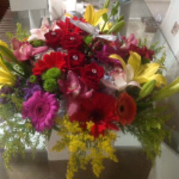Colorful mixed bouquet with red, yellow, pink, and purple flowers in a low arrangement.