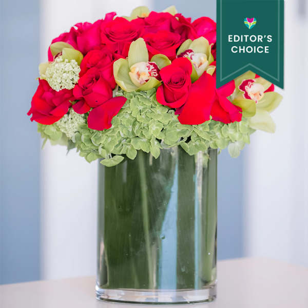 Pink roses and green orchids in a clear glass vase.