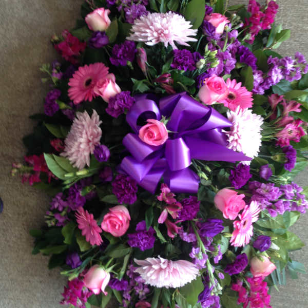 Purple and pink floral wreath with a large ribbon bow