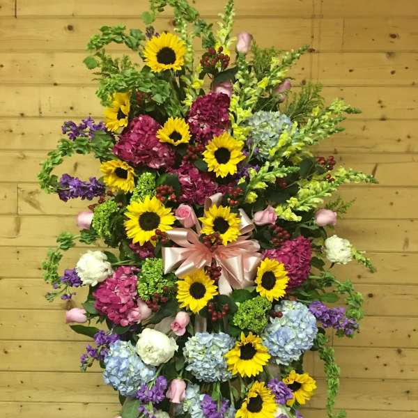 Large standing floral spray with sunflowers, hydrangeas, and ribbon