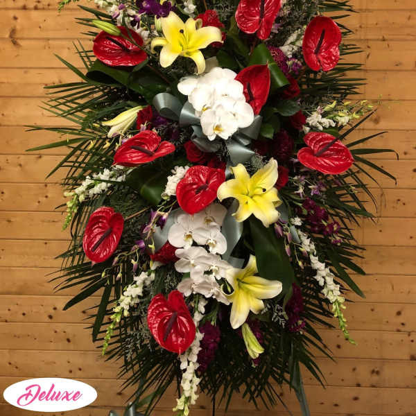 Standing floral spray with red anthuriums, yellow lilies, and white orchids