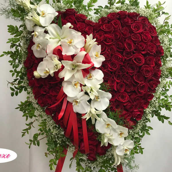 Heart-shaped red rose arrangement with white orchids and a red ribbon