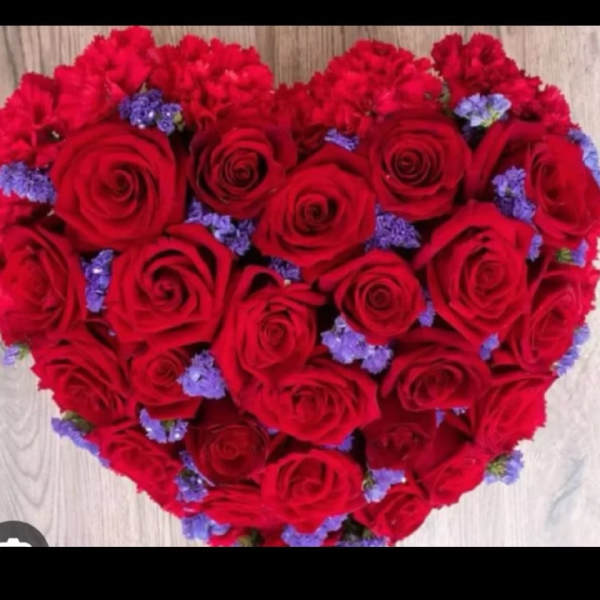 Heart-shaped bouquet of red roses with small purple filler flowers