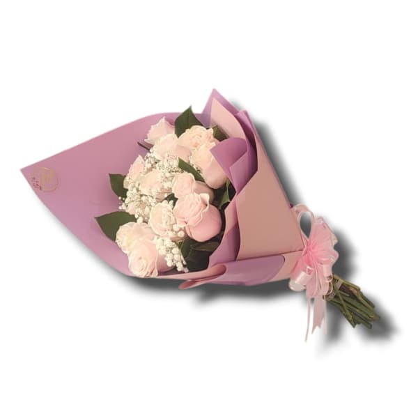 Hand-tied bouquet of light pink roses and white filler flowers wrapped in pink and lavender paper.