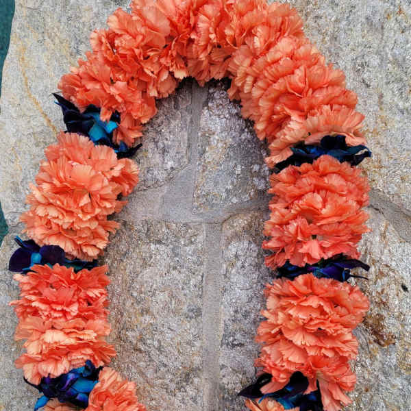 Orange carnation lei with dark blue ribbon accents