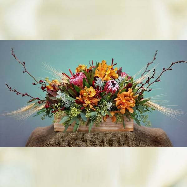 Mixed floral arrangement in a wooden box with orange and pink blooms