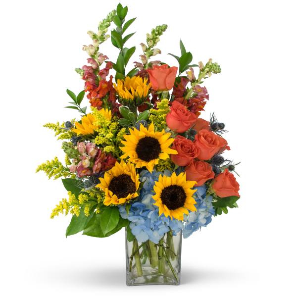 Mixed bouquet with sunflowers, orange roses, and blue hydrangeas in a glass vase