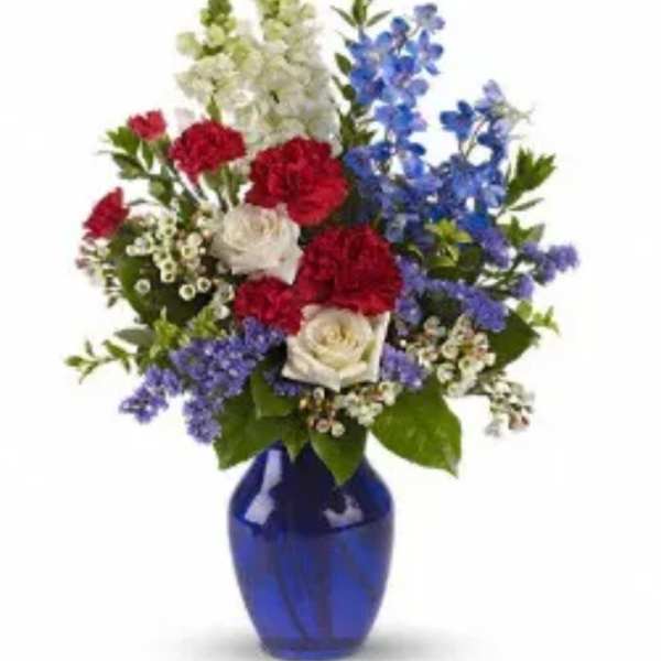 Red, white, and blue flowers arranged in a cobalt vase