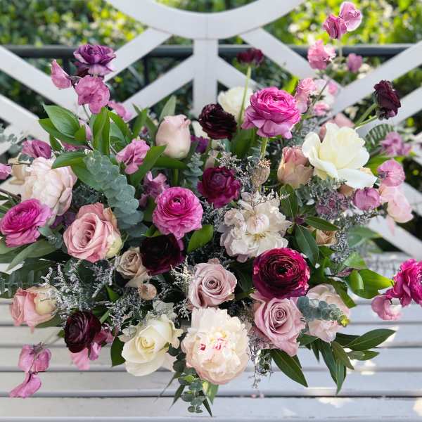 Mixed bouquet of pink, white, and burgundy flowers on a white bench