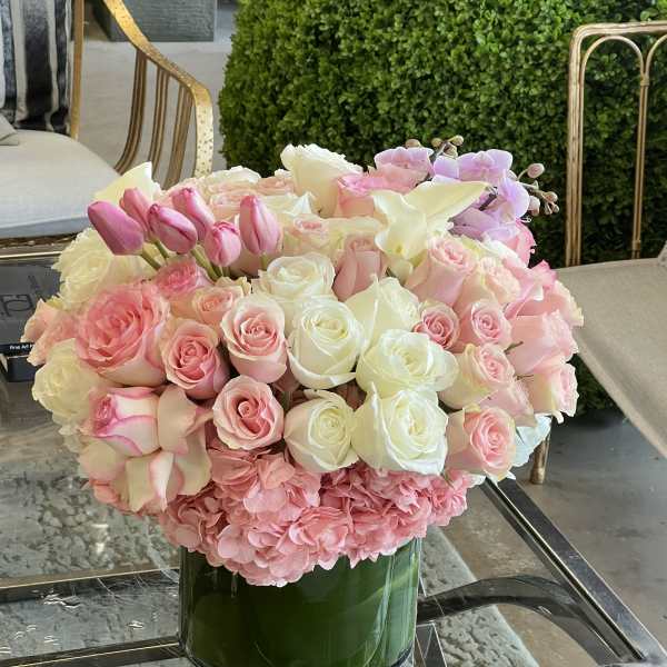 Pink and white roses with tulips and orchids in a glass vase