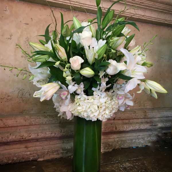 White lilies and pale pink roses in a tall green vase