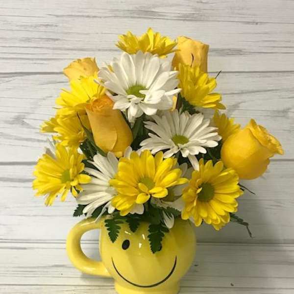 Yellow and white daisy bouquet in a smiley-face mug
