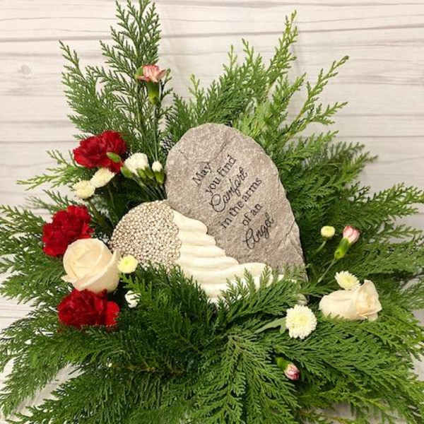 Sympathy floral arrangement with red and white flowers around a memorial stone