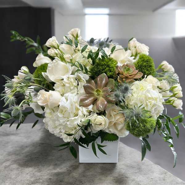 White floral arrangement with succulents in a square vase