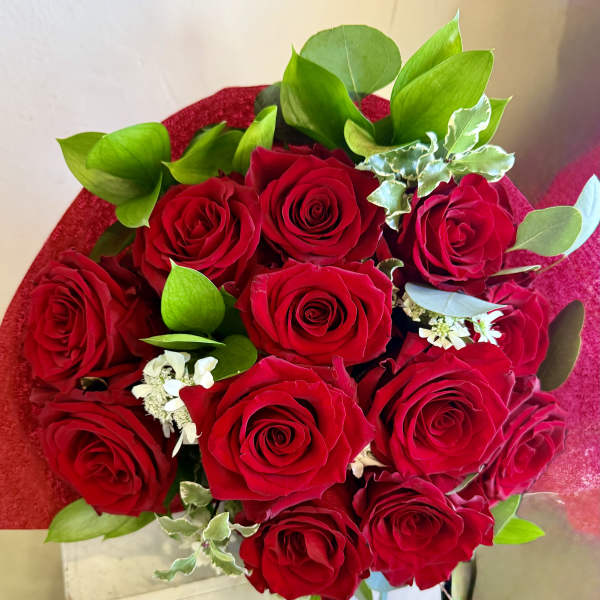 Bouquet of red roses with green foliage and small white filler flowers