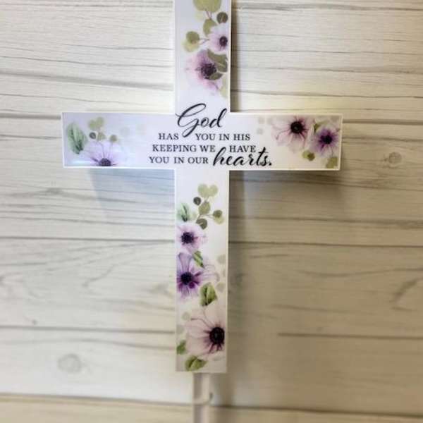Floral cross sign with a sympathy message on a stake