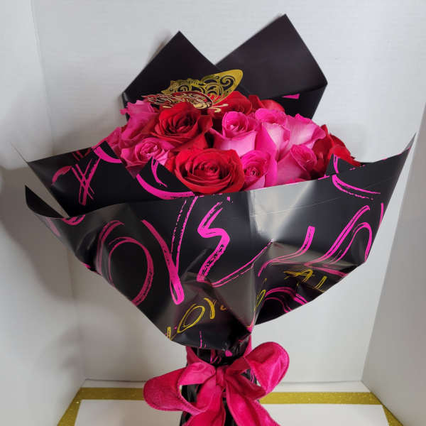 Bouquet of pink and red roses wrapped in black paper with a pink ribbon