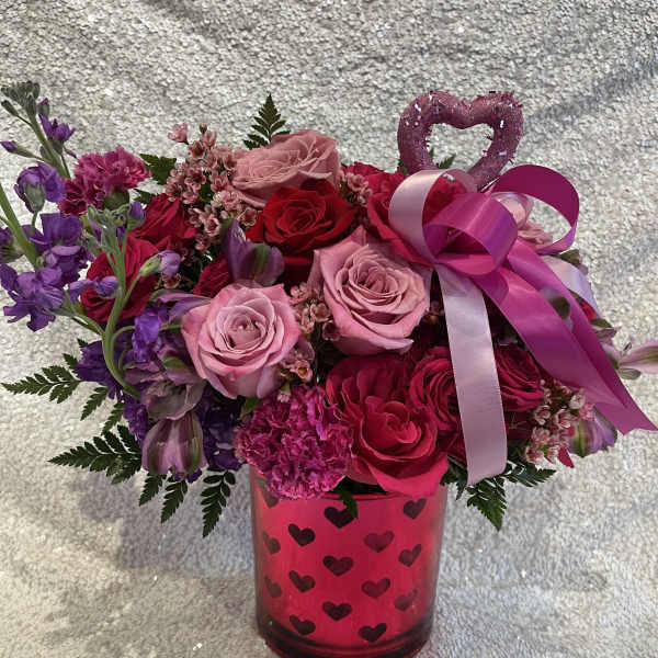 Pink and red rose bouquet in a heart-patterned vase with ribbon and heart topper