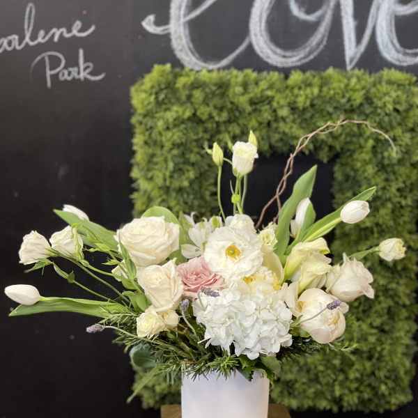 White floral arrangement in a white vase with pink accents