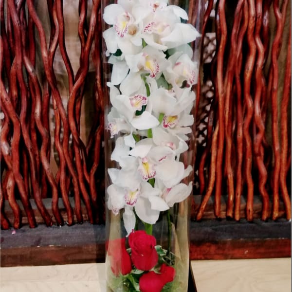 Tall glass vase with white orchids and red roses