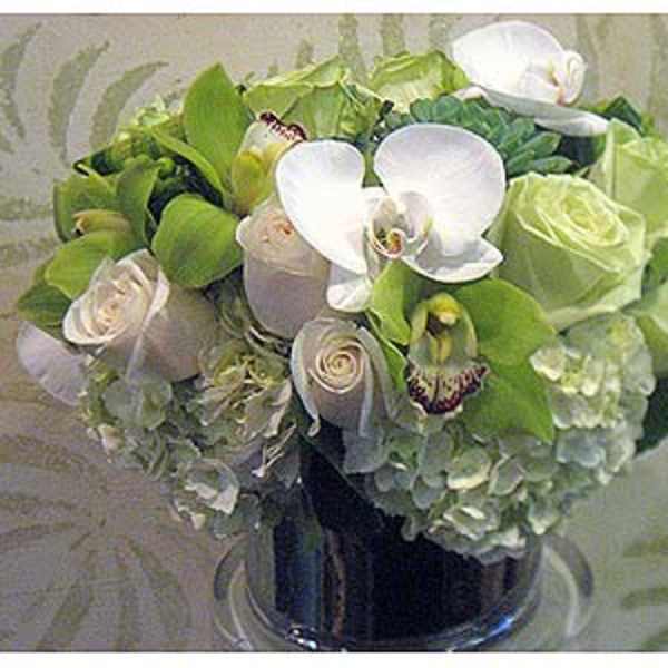 Bouquet of white orchids, pale roses, and green hydrangeas in a vase