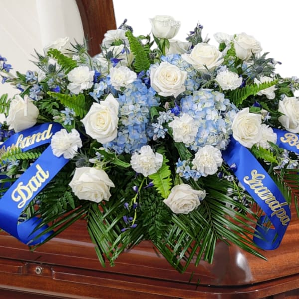 White rose and blue hydrangea casket spray with blue ribbons