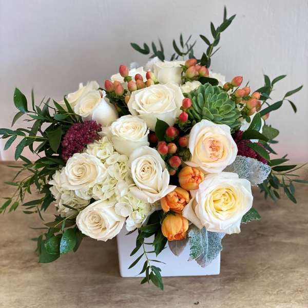 White roses and succulents arranged in a white box