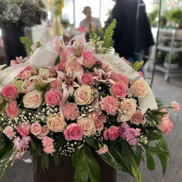 Large pink and cream rose arrangement with ribbons and lilies